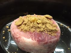 a large piece of meat sitting on top of a black pan covered in crumbs