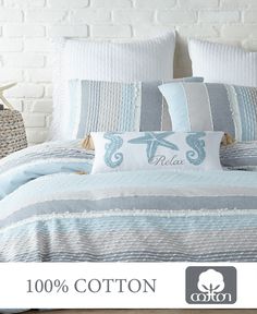 a bed covered in blue and white pillows next to a basket with seahorses on it