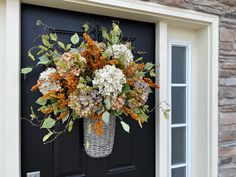 a basket filled with lots of flowers sitting on top of a door sill next to a black door