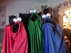 three children's halloween costumes are lined up in front of a door with eyes on them