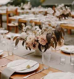 the table is set with white plates and silverware, flowers in vases, and napkins