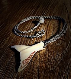 a necklace with an animal's tooth on it sitting on a wooden table next to a pair of scissors