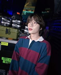 a young man wearing glasses standing in front of luggage