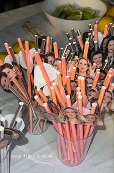 a vase filled with orange and white pencils next to pictures of people on them