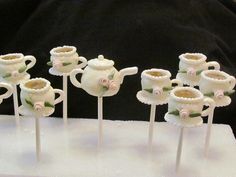 there are many small teapots on sticks with flowers in them sitting on a table