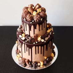 a three tiered cake with chocolate and nuts on top