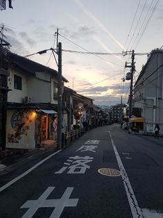 an empty street with buildings on both sides and power lines in the background at sunset