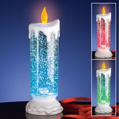 a lit candle that has been decorated with snow and colored lights on the top, in front of a blue background