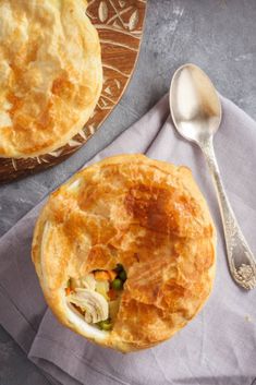 two pies sitting on top of a wooden tray next to a spoon and fork