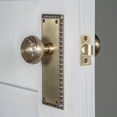 a door handle on a white door with a gold plated knob and an ornate design