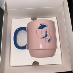 a pink and blue coffee mug in a box