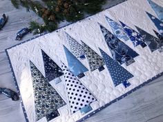 a quilted table runner with blue and white christmas trees on the top, surrounded by confetti cones