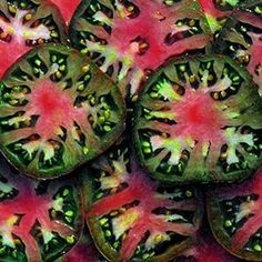 several slices of green and red tomato on top of each other with yellow spots in the middle