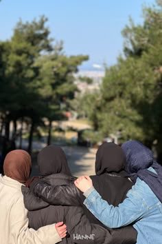 three people in black jackets are sitting on a bench and one is holding the other's back