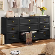 a black dresser with yellow drawers and clothes hanging on the rack in front of it