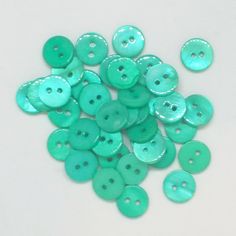 a pile of green buttons sitting on top of a white table