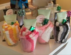 four small glass vases filled with candy and candies on a counter top next to each other