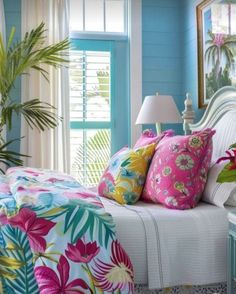 a bedroom with blue walls and white bedding has colorful flowers on the comforter