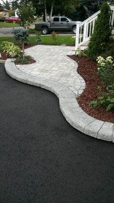 a driveway that has been paved and is surrounded by landscaping