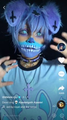 a person with blue makeup and cat ears on their head is holding her hands up in front of her face