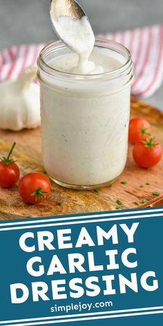 creamy garlic dressing in a glass jar with a spoon and cherry tomatoes on the side