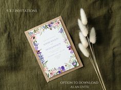 the wedding stationery is laid out next to some pamonini and feathers on a green cloth