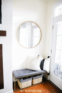 a living room with white walls and wood flooring, a round mirror on the wall