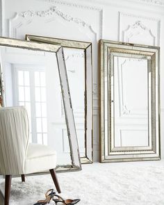 a pair of shoes sitting on the floor in front of two mirrors and a chair