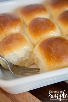 a white dish filled with rolls and a fork