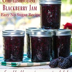 four jars filled with blackberry jam sitting on top of a table