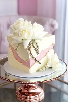 a white and pink cake sitting on top of a glass table next to a couch