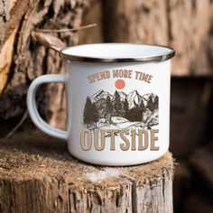 a white enamel mug with the words spend more time outside on it sitting on a tree stump