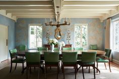 a dining room table with green chairs and a chandelier hanging from the ceiling