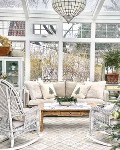 a living room filled with furniture next to a window covered in snowing plants and greenery