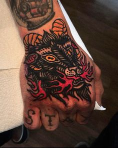 a person's hand with tattoos on it and an image of a demon in the middle