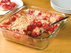 a casserole dish with strawberries in it and two plates on the side