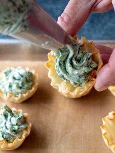 someone using a knife to cut spinach in small cupcakes on a cutting board