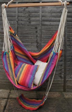 a colorful striped hammock hanging from a wooden pole with two pillows on it