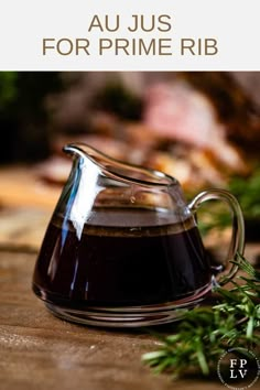 a glass pitcher filled with liquid sitting on top of a wooden table next to leaves