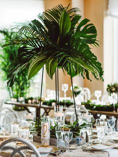 the table is set with white linens and greenery