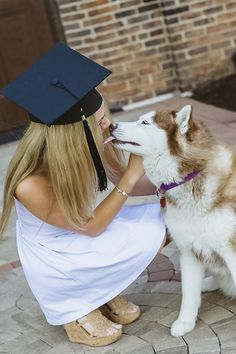 a woman kneeling down next to a dog wearing a graduation cap