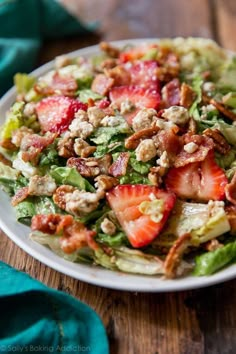 a salad with strawberries, lettuce and walnuts in it on a white plate