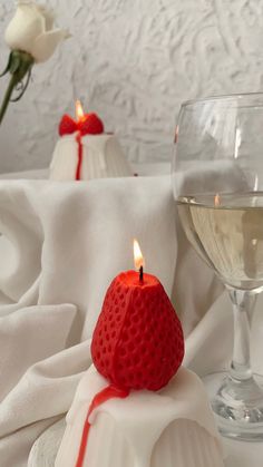 a red candle sitting on top of a white cake next to a glass of wine