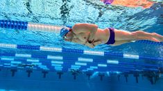 a woman swimming in a pool wearing a blue and white swim suit with her hands under the water's surface