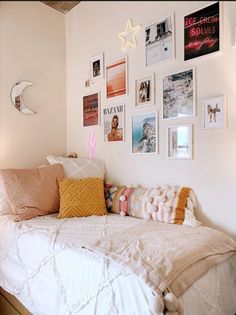 a bed with lots of pillows and pictures on the wall next to it in a bedroom