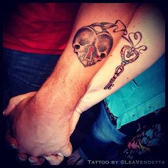 two people are holding hands with tattoos on their arms and the other hand has a key in it