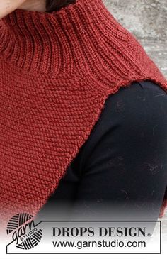 a woman wearing a red knitted sweater and black pants with her hands in her pockets