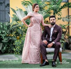 a man and woman posing for a photo in front of some plants on the grass