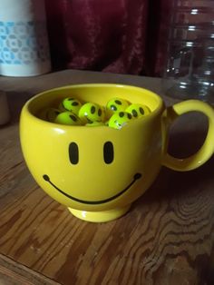 a smiley face cup filled with balls on top of a wooden table