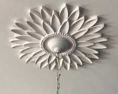 a white flower is hanging from the ceiling with beads on it's end,